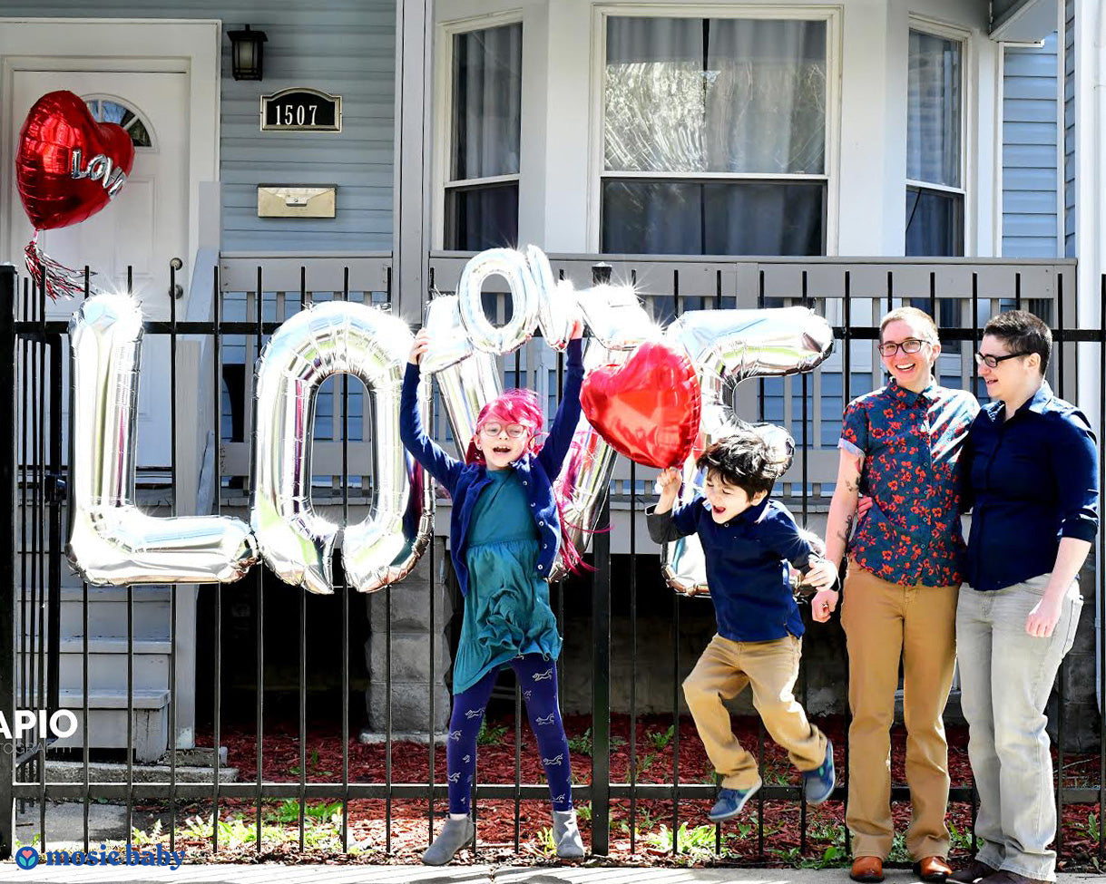 transgender couple with their two children, celebrating their new pregnancy