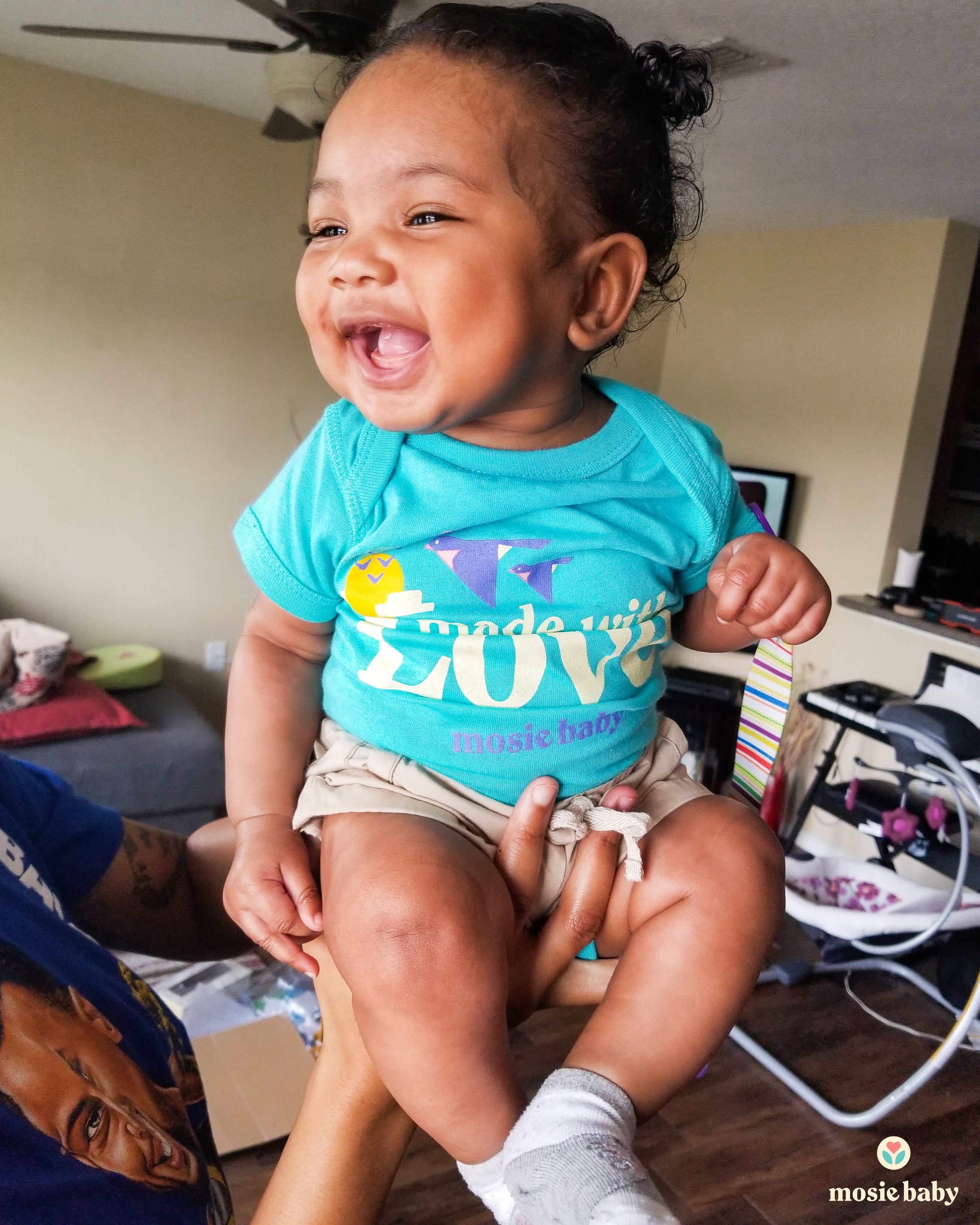 smiling baby wearing a mosie baby onesie that say made with love